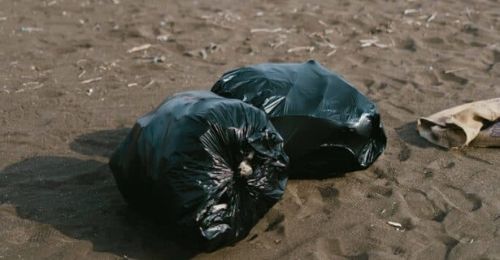 Une Poubelle Dans Une Salle De Bain Avec Un Sac Poubelle Blanc Sur Le Sol.